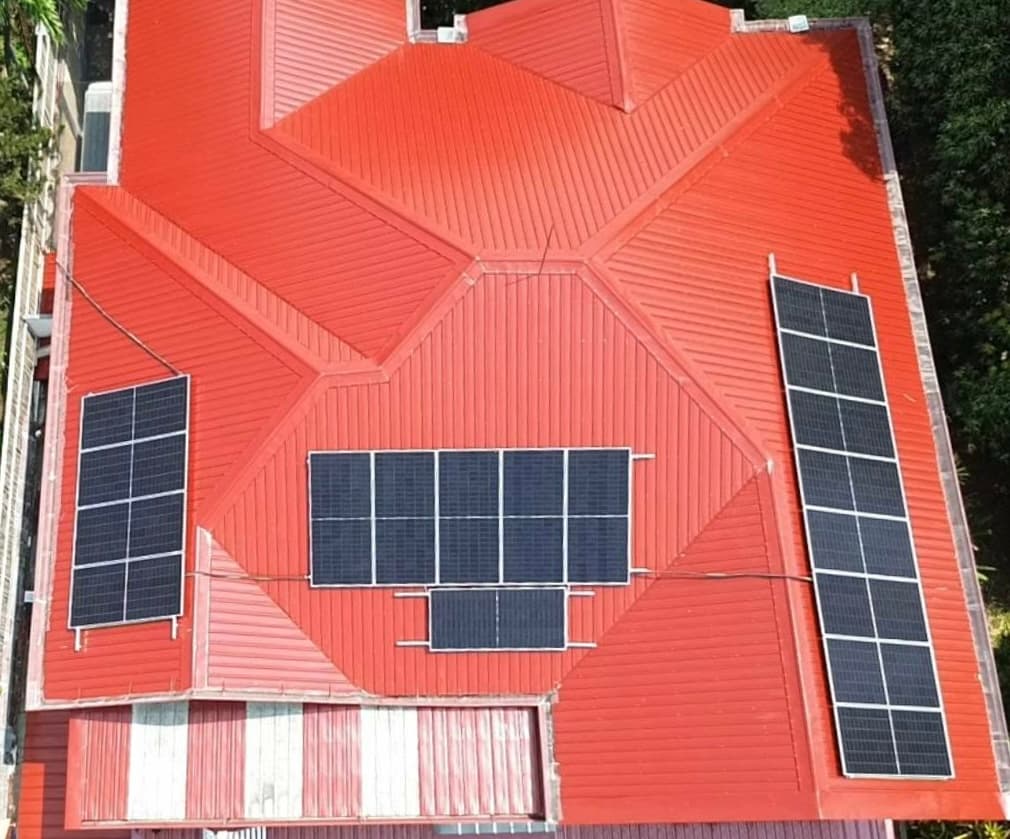 Aerial view of the finished Muntinlupa system, with three separate solar arrays laid out across the home's red metal roof.